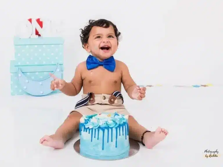 A playful toddler covered in cake during a cake smash photoshoot