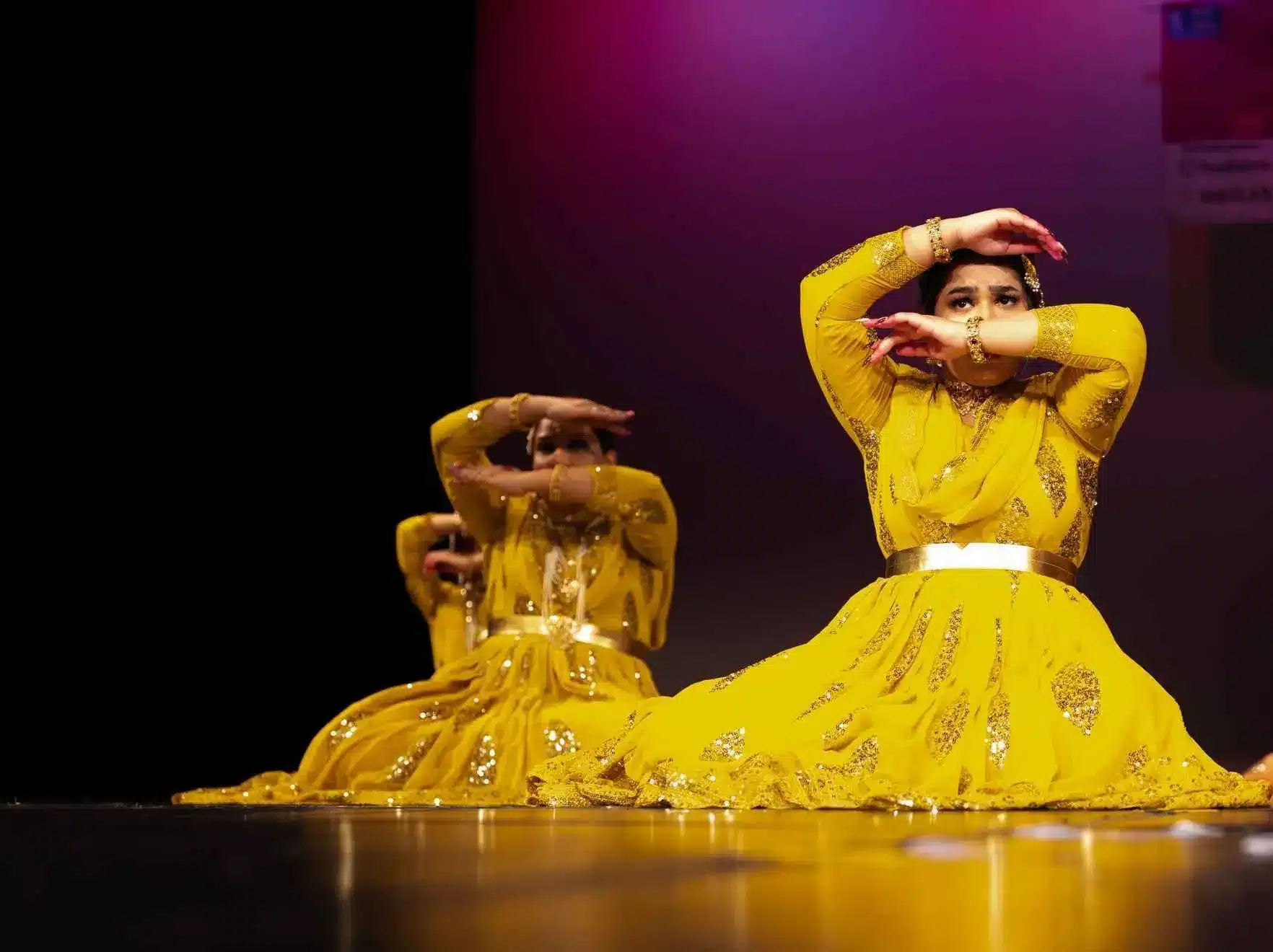 Mesmerizing Indian Dance Performance: Young girls dressed in traditional Indian attire, gracefully performing on stage in vibrant yellow dresses during a stage show in Wellington