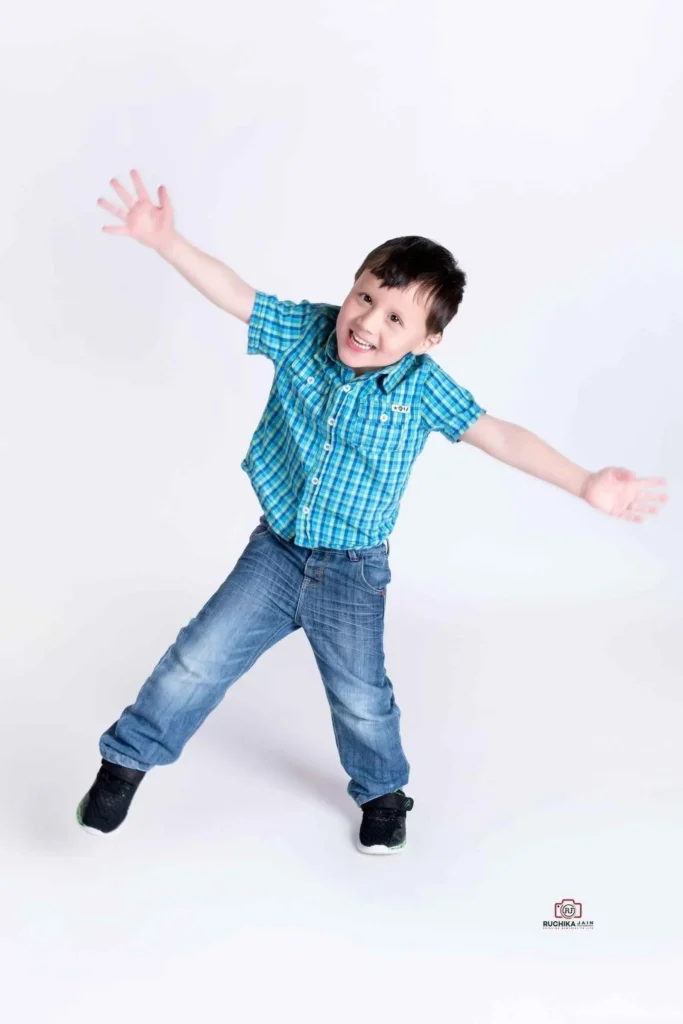 Happy young boy jumping with arms wide open during a fun studio photoshoot by Ruchika Jain Photography in Wellington, New Zealand