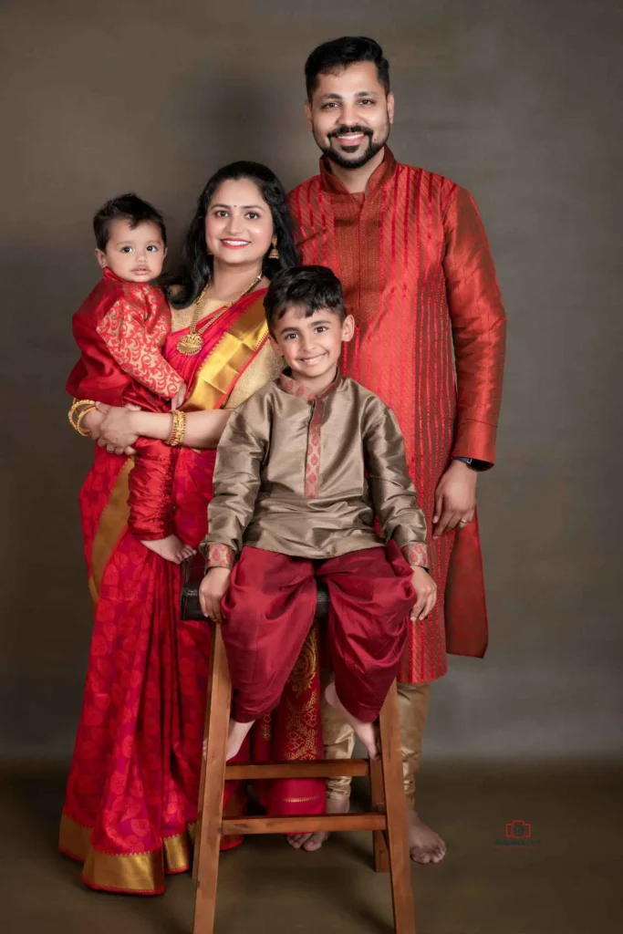 Captivating family photography portraying a well-coordinated maroon-themed family, including parents and two kids, against a warm brown background at Studio Wellington, New Zealand