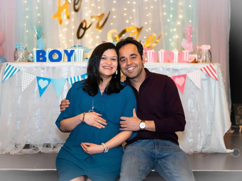 oyful Baby Shower Celebration: A couple smiling in front of a beautifully decorated wall at a baby shower event
