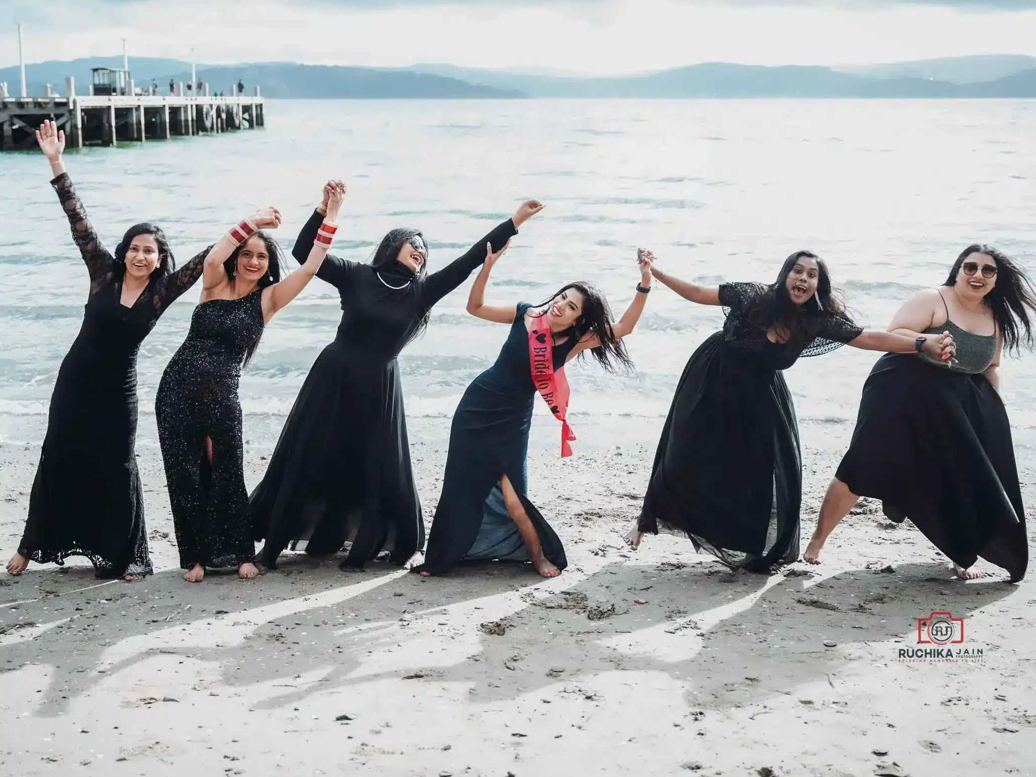 Beach Bachelorette Party Fun: A group of friends joyfully dancing and holding hands on the beach during a bachelorette party