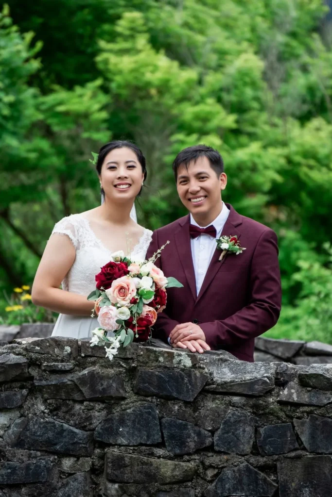 Wedding photography in Wellington: Happily married couple blushing in love while standing on a lake bridge.