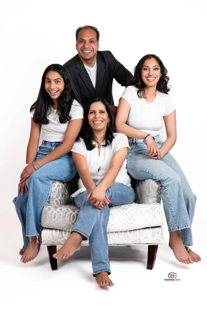 Radiant family portrait photography featuring ladies in white shirts and blue jeans, and a man wearing a black coat, all smiling against a pristine white background at Studio Wellington, New Zealand