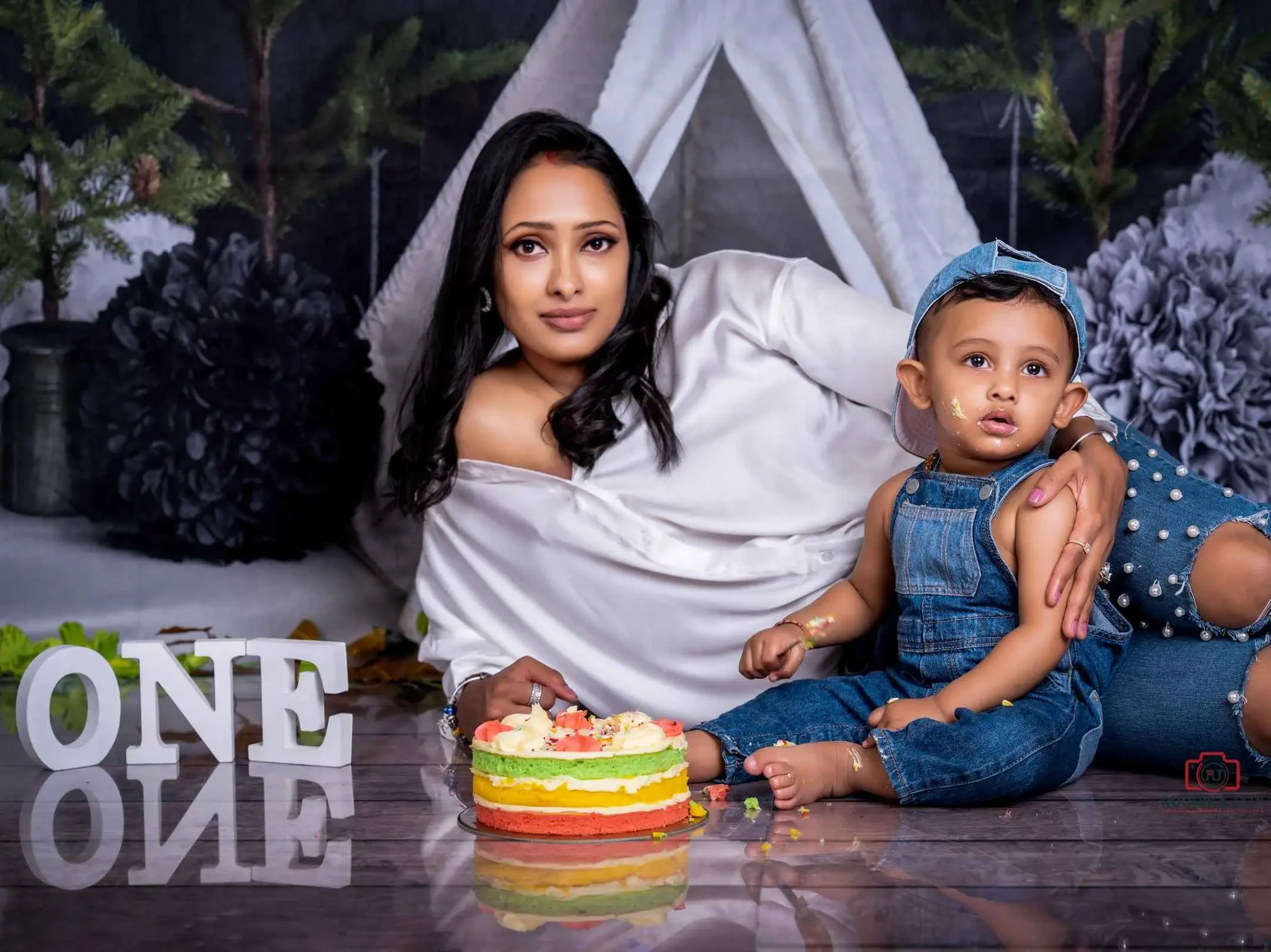 Cute toddler surrounded by cake crumbs and frosting in a cake smash session