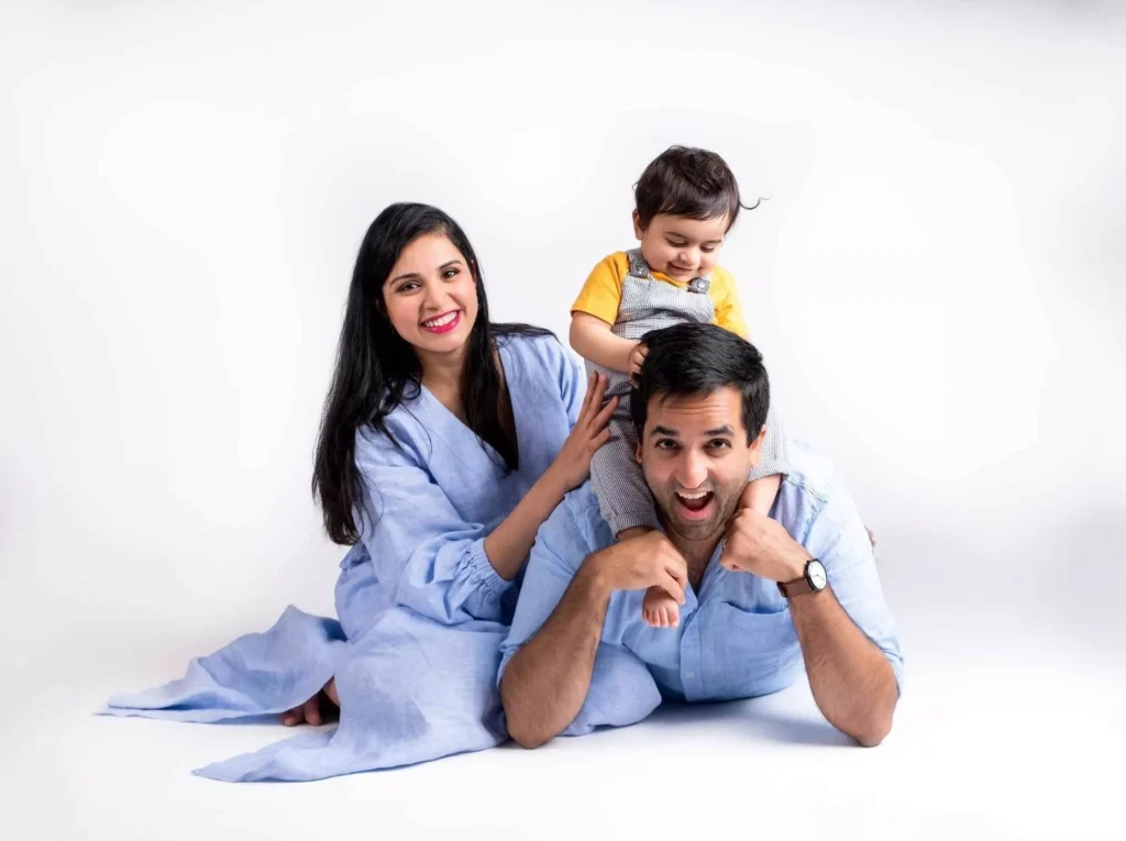 Charming portrait of husband, wife, and their son in matching colored dresses, set against a light background - Dress for Family Photoshoot Guide