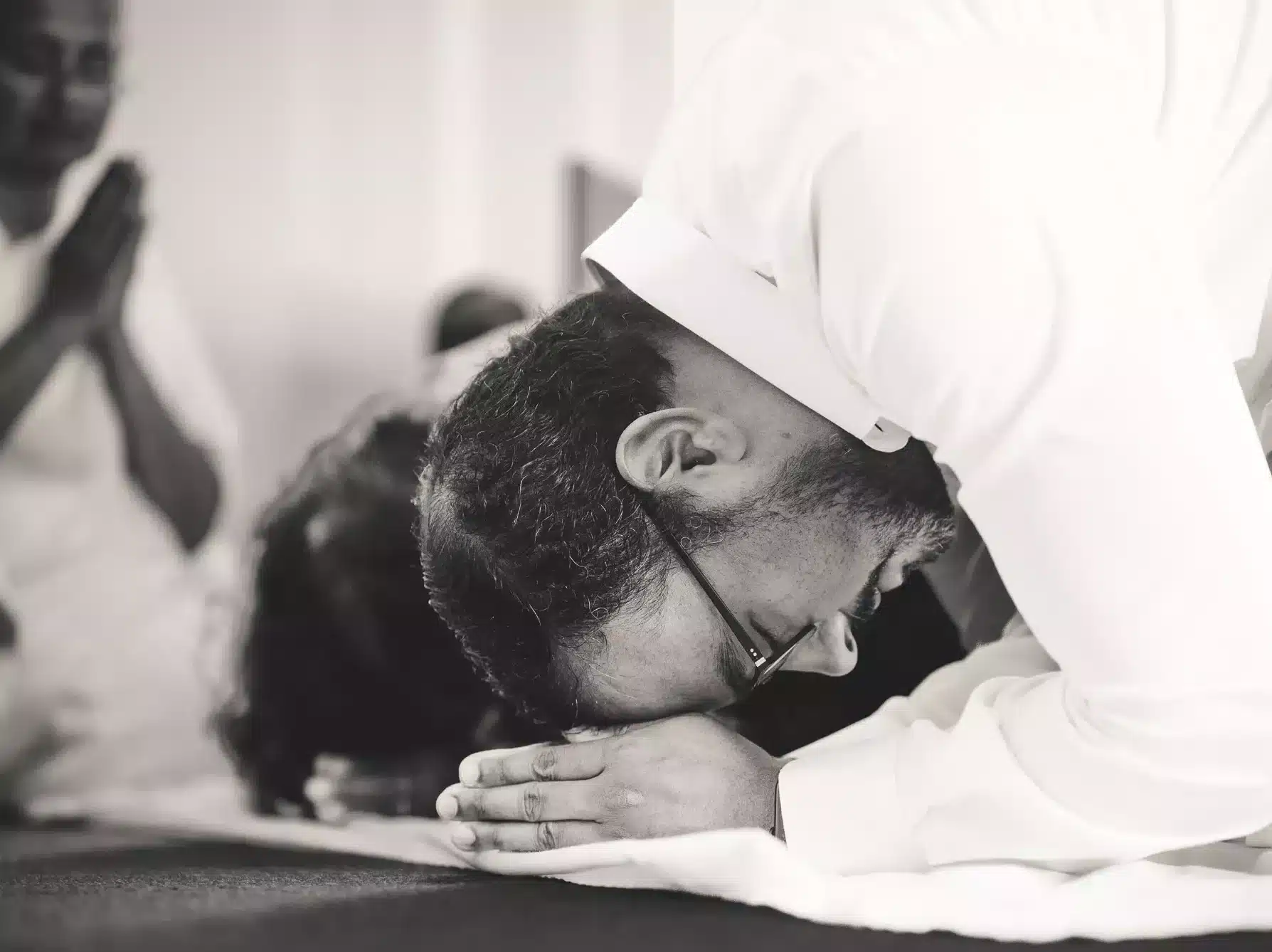 A Moment of Reverence: An Indian man bowing down with hands together on his forehead during a funeral, captured in a poignant black and white photograph