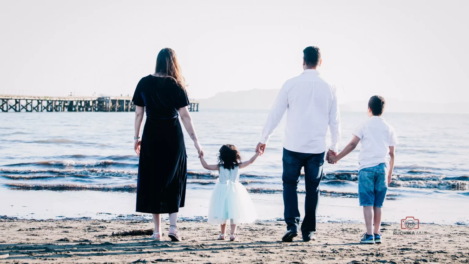 Heartwarming family portrait from behind, gazing at the beauty of the ocean on the beach - Dress for Family Photoshoot Guide.