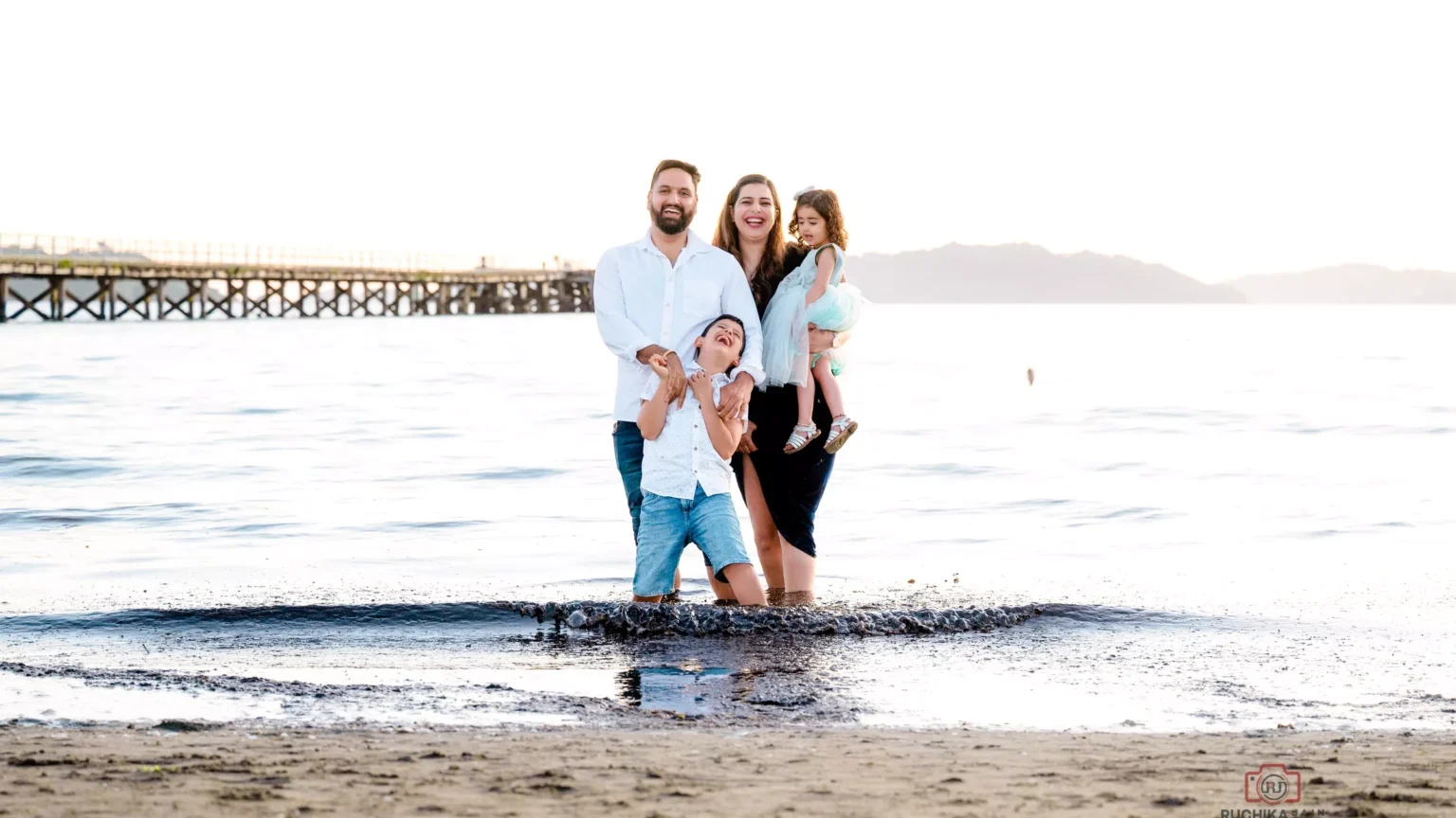 Adventurous family portrait standing in water on a beach - Dress for Family Photoshoot Guide