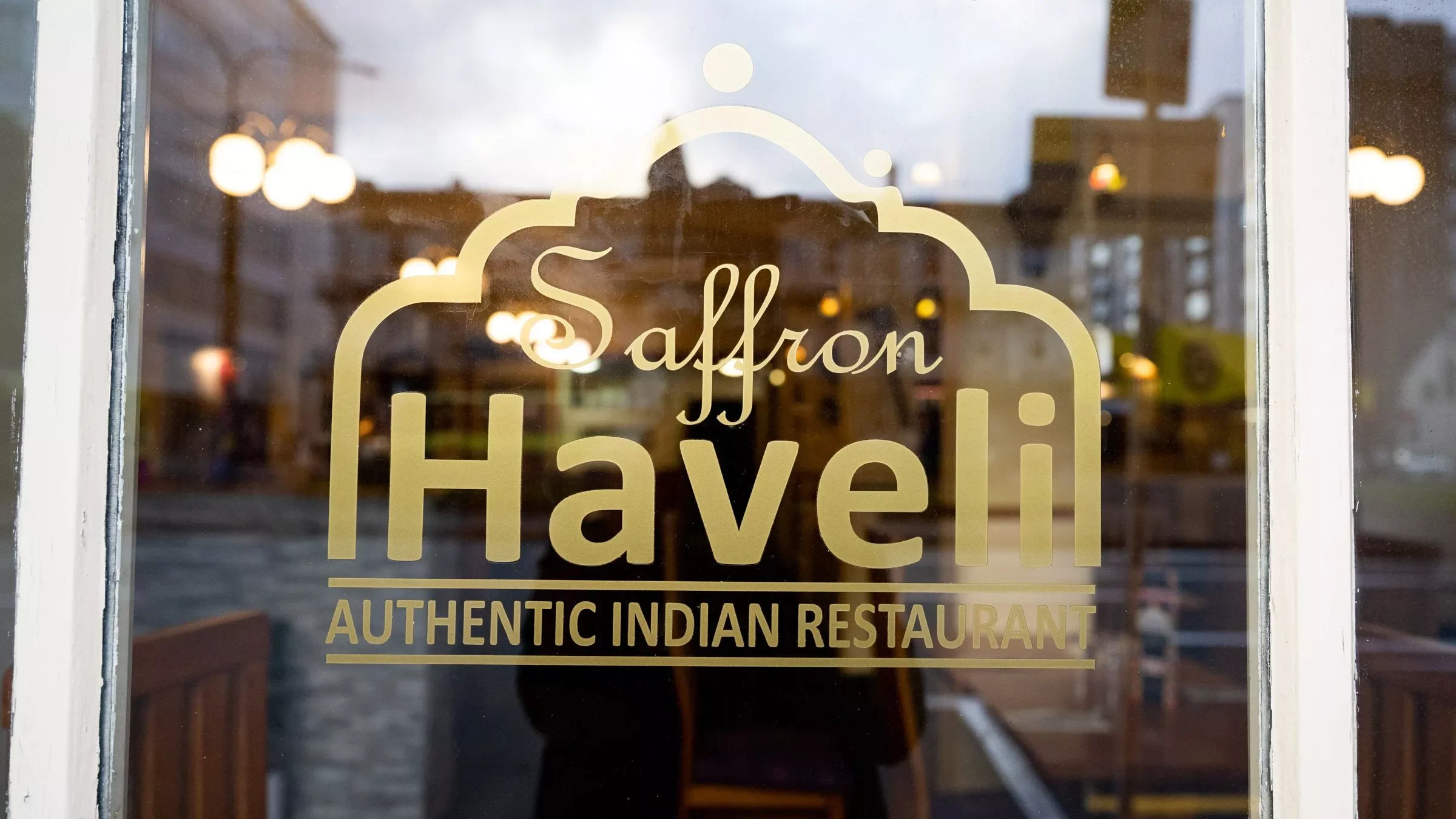 Commercial Photography: Glass door with 'Saffron Haveli' inscription, welcoming guests to an Indian restaurant in Wellington, New Zealand.