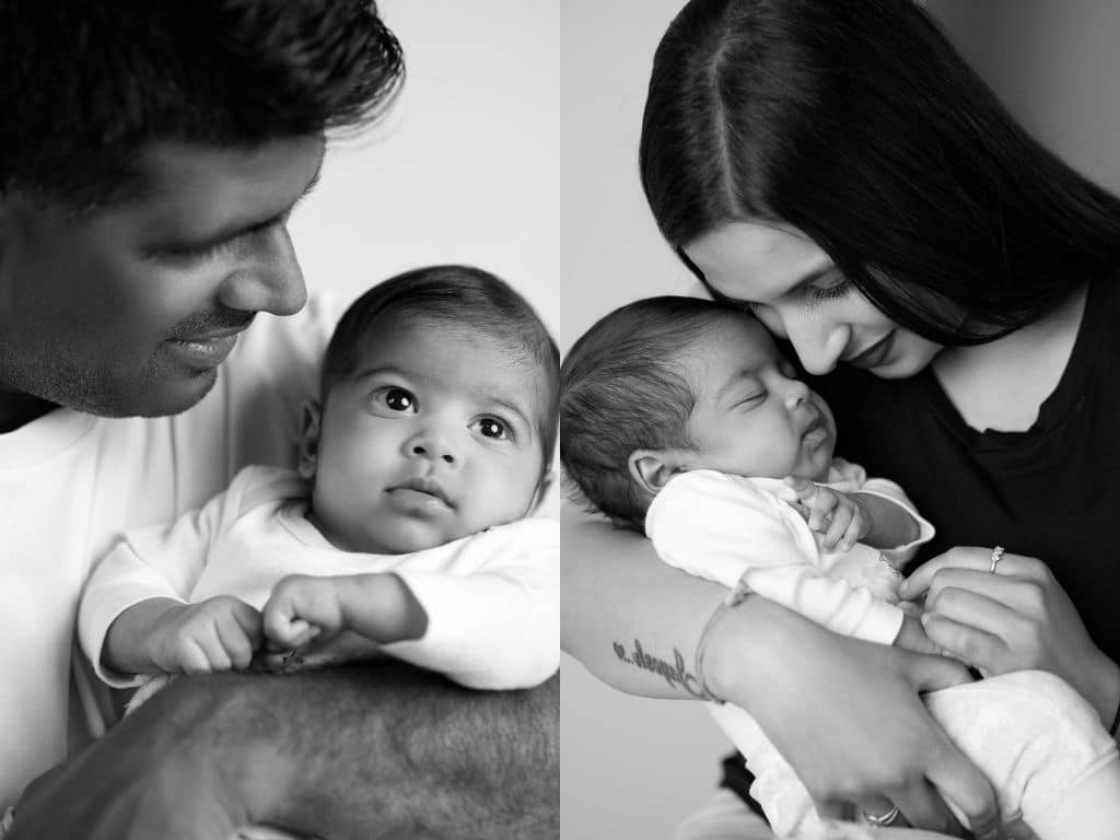 Mom and dad passionately embracing their newborn baby in black and white dramatic mood