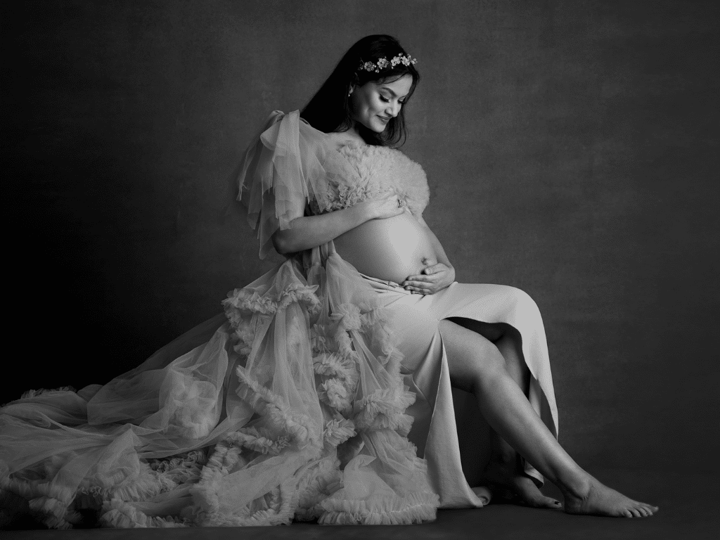 A stunning black-and-white maternity portrait of a glowing mom-to-be in an elegant gown, capturing the grace and beauty of pregnancy
